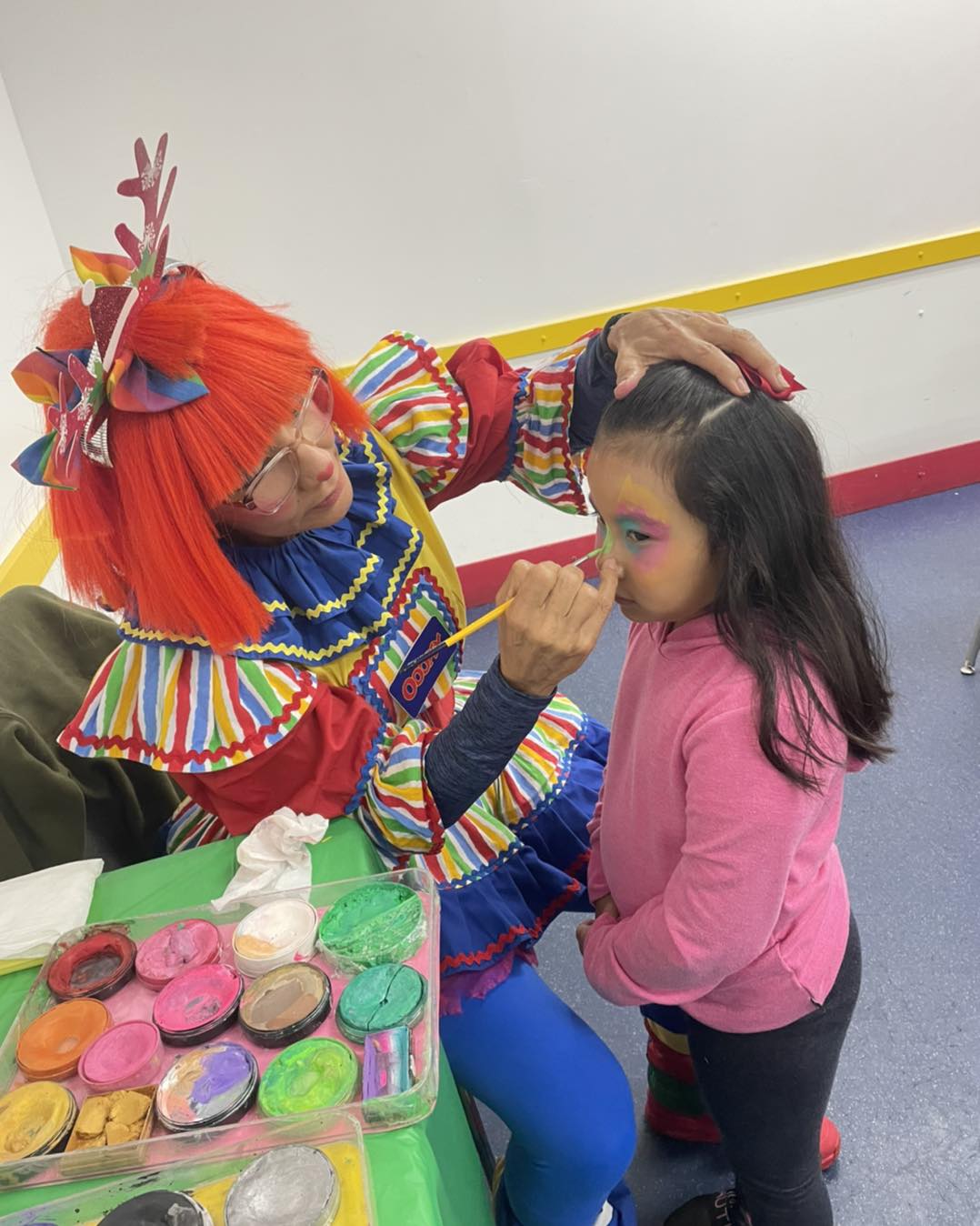 clown painting girl's face at kids' party
