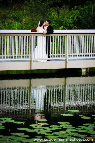 bride and groom kissing on bride over pond
