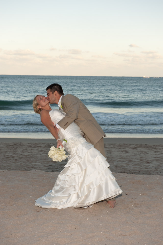 groom kissing bride on the beach