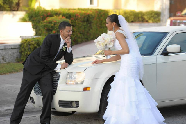 bride and groom posing with limo